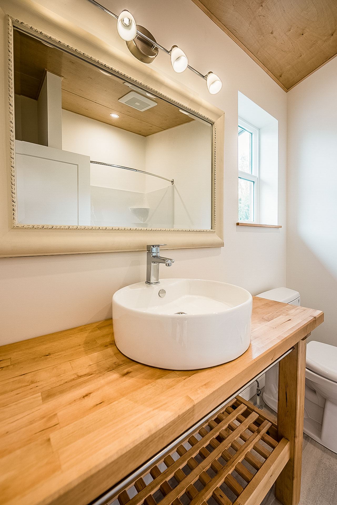 A wood bathroom vanity and round white sink in a home built by Eisenhauer Woodworks