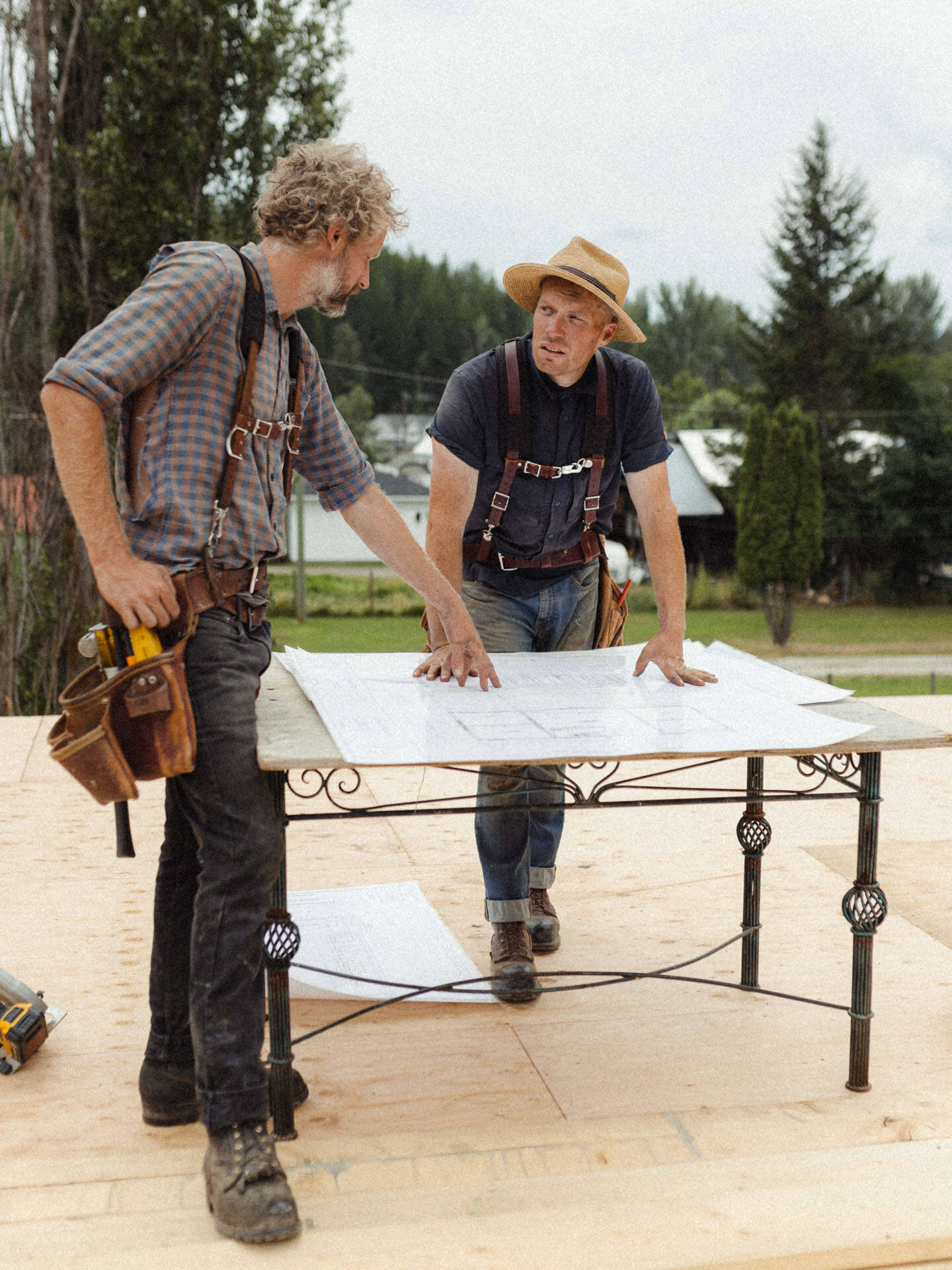 Two workers at Eisenhauer Woodworkers standing over a wood table looking at building plans in Kimberley BC